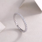Silver ring with small diamonds on a light gray background