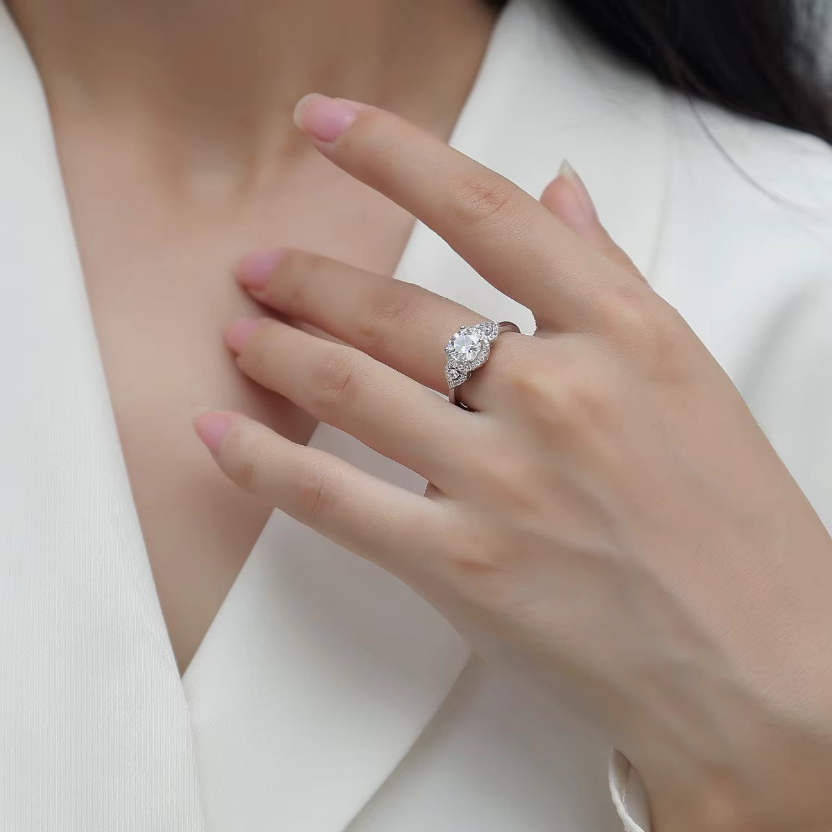 Close-up of a hand wearing a diamond ring on a white background