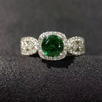 Silver ring with a green gemstone on a black textured surface