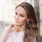 Woman with long, wavy hair wearing earrings, with a blurred background