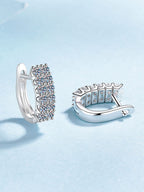 Silver hoop earrings with clear gemstones on a light blue background