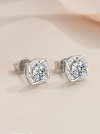 Silver earrings with clear gemstones on a beige background