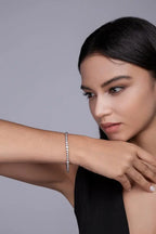 Model wearing a delicate white gold tennis bracelet, photographed in a refined studio setting