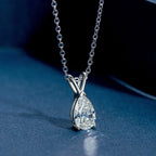 Silver necklace with a teardrop-shaped diamond pendant on a blue surface