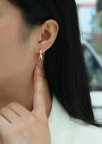 Close-up of a person wearing a gold earring with a letter 'A' design.