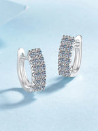 Pair of silver hoop earrings with clear gemstones on a light blue background