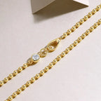 Gold chain with a diamond clasp on a light pink background