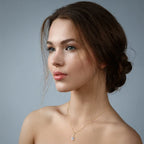 Woman wearing a gold necklace with a pendant against a gray background