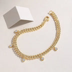 Gold chain bracelet with small round charms on a light background