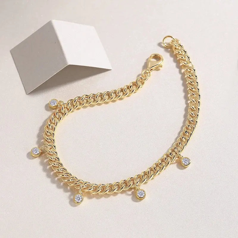 Gold chain bracelet with small round charms on a light background