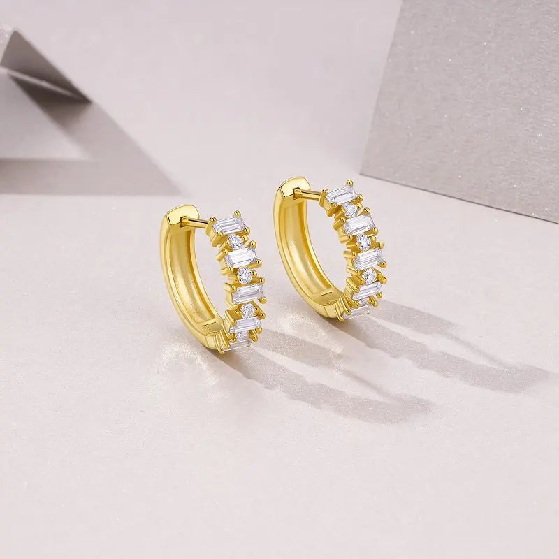 Gold hoop earrings with clear stones on a light gray background