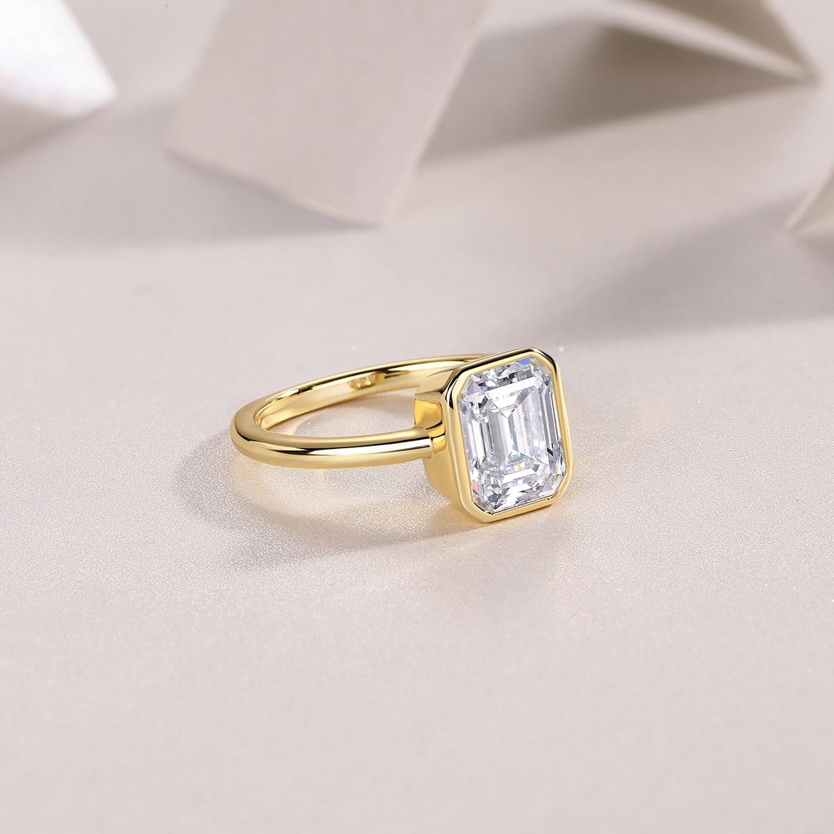 Gold ring with a large diamond on a soft beige background