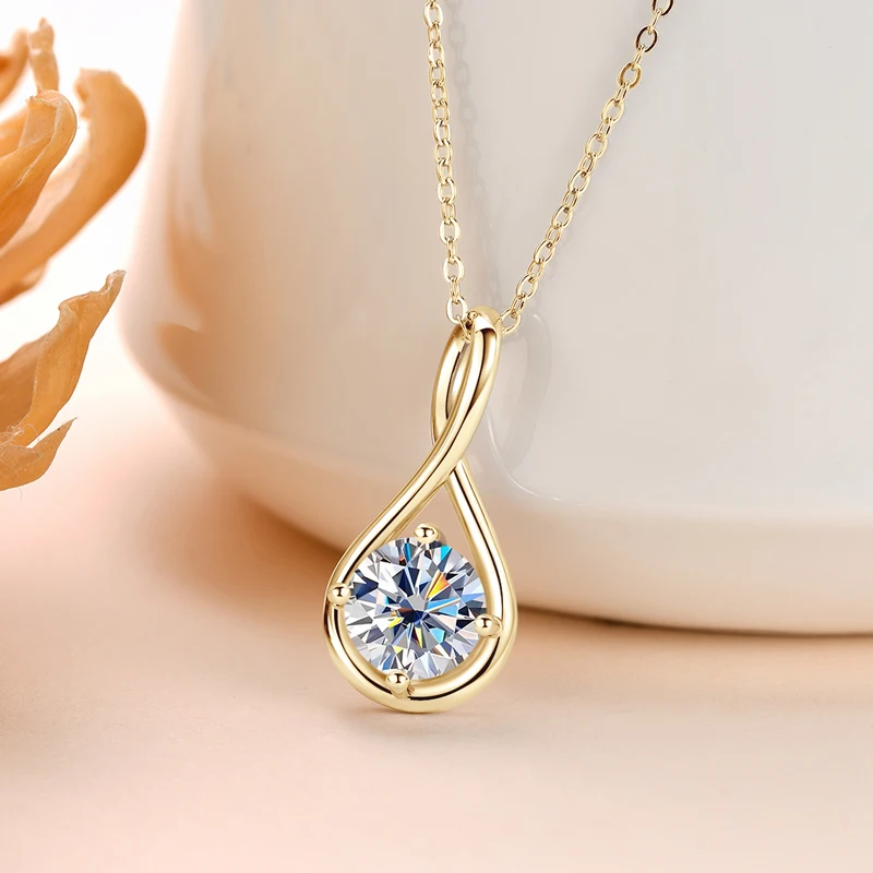 Gold necklace with a teardrop-shaped pendant featuring a large gemstone on a soft background.