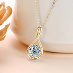 Gold necklace with a teardrop-shaped pendant featuring a large gemstone on a soft background.