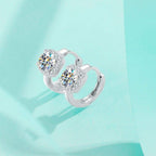 Silver earrings with clear gemstones on a light blue background