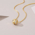 Gold pendant necklace with pavé moissanite accent on a delicate chain displayed on a soft neutral background