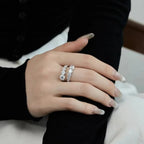 Hand wearing two diamond rings on a neutral background