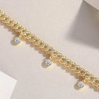 Gold bracelet with diamond charms on a light pink background