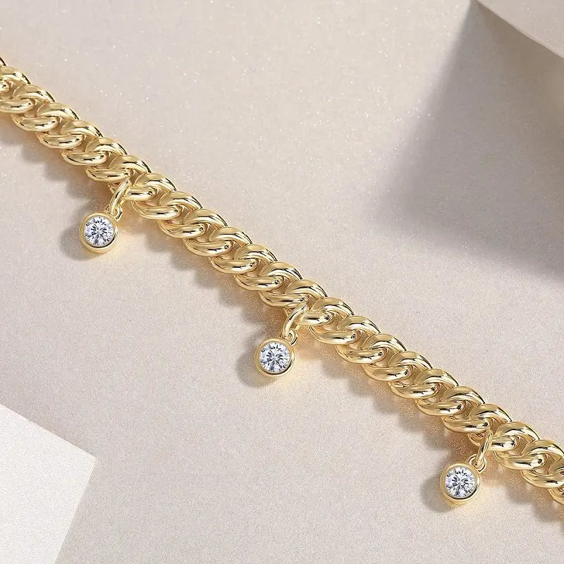 Gold bracelet with diamond charms on a light pink background