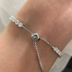 Silver bracelet with clear stones on a wrist against a neutral background