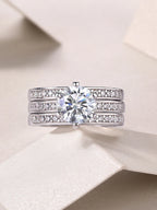 Silver ring with a large diamond and smaller diamonds on the band against a light background