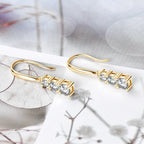 Gold earrings with clear stones on a decorative surface