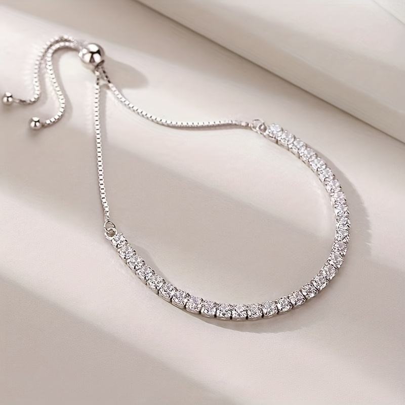 Silver necklace with clear stones on a light beige surface