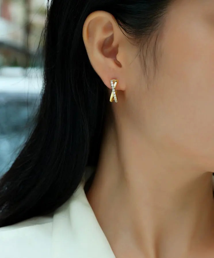 Close-up of a person wearing gold hoop earrings with a blurred background