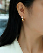 Close-up of a person wearing gold hoop earrings with a blurred background