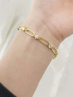 Gold bracelet with clear stones on a wrist against a white background