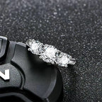 Silver ring with three clear gemstones on a textured black surface