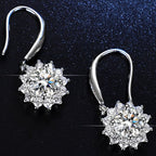 Pair of silver earrings with clear gemstones on a black background