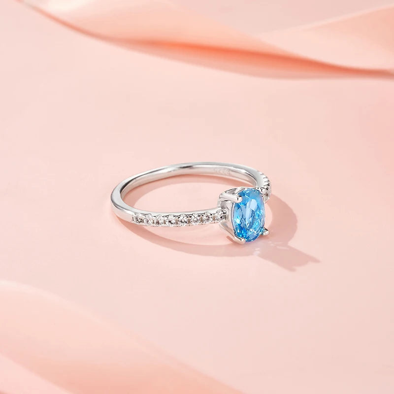 Silver ring with a blue gemstone on a soft pink background