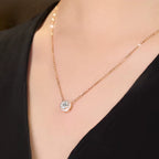 Rose gold necklace with a diamond pendant on a person wearing a black top.