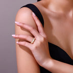Hand with a gold ring on a shoulder against a neutral background