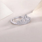 Silver ring with a heart-shaped center on a light pink background