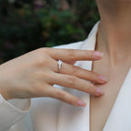 Hand wearing a silver ring with a blurred green background