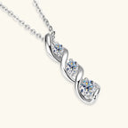 Silver necklace with heart-shaped pendant featuring three diamonds on a white background