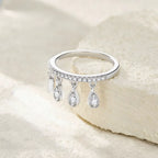Silver ring with teardrop-shaped stones on a light beige background
