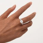 Silver ring on a person's finger against a plain background