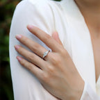 Hand wearing a diamond ring with a blurred background