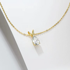 Gold necklace with a teardrop-shaped diamond pendant on a light gray background