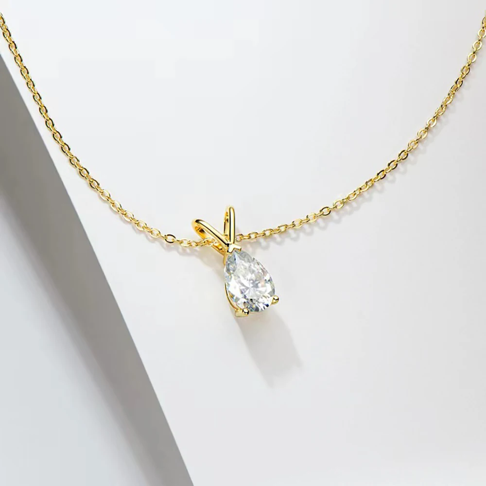 Gold necklace with a teardrop-shaped diamond pendant on a light gray background