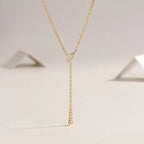 Gold necklace with a delicate pendant on a light gray background
