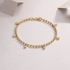 Gold bracelet with small crystals on a light gray background