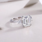 Diamond ring with emerald-cut gemstone on a light background