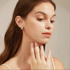 Woman wearing gold earrings with a neutral background