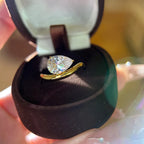 Gold ring with a diamond in a black jewelry box held by a hand.