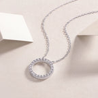 Silver necklace with a circular pendant on a beige background