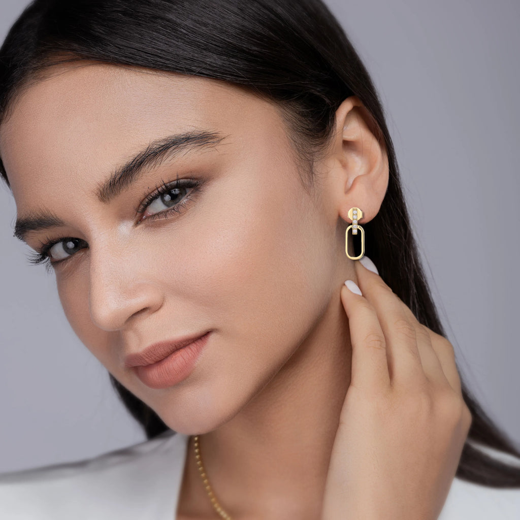 Woman wearing gold earrings with a neutral background